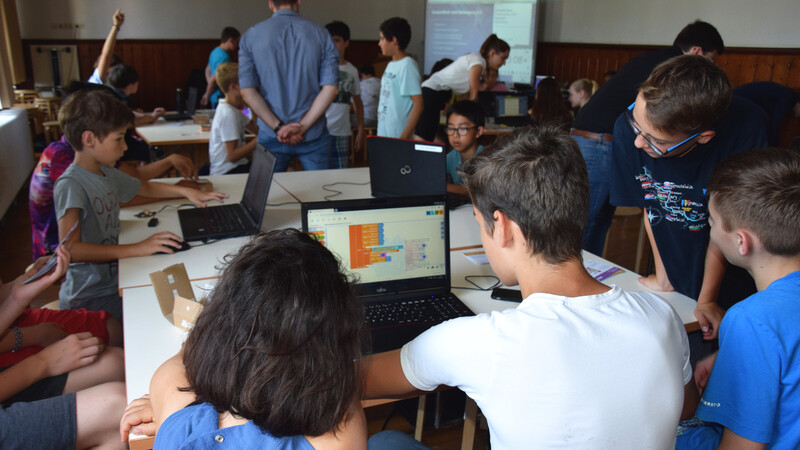Schüler und eine Mentorin arbeiten gemeinsam am Laptop.