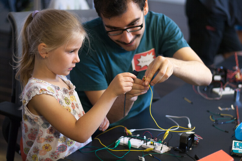 Ein Mädchen im Grundschulalter und Tutor im Workshop programmieren gemeinsam einen Roboter mit Makey Makey.